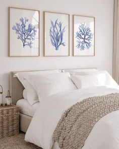 three blue and white paintings hang above a bed