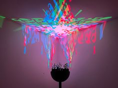 a colorful object is lit up in the dark with neon colors on it's surface