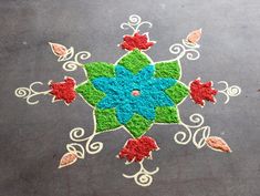 an artistic design on the ground with leaves and flowers painted on it in blue, green, red and white colors