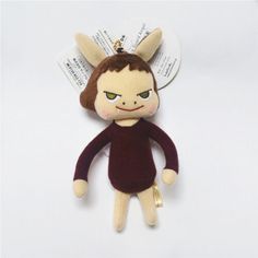 a small stuffed animal with green eyes and brown hair, wearing a maroon dress is sitting on a white surface