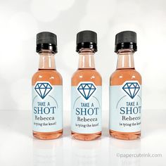 three bottles of alcohol sitting next to each other on a white counter top, one has a diamond in it