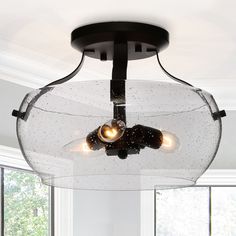 a glass light fixture hanging from the ceiling in a room with white walls and windows