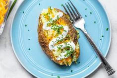 a blue plate topped with an open face potato covered in sour cream and chives