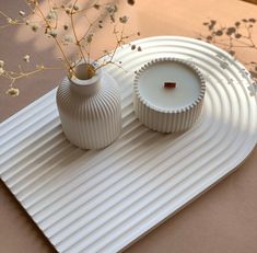 two white vases sitting on top of a table next to each other with flowers in them