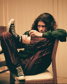 a young man sitting on top of a wooden chair