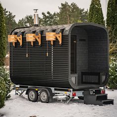 a black trailer is parked in the snow