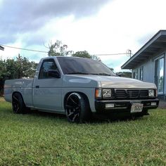 a silver truck parked on top of a lush green field next to a house in the background