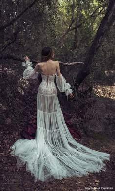 a woman in a white dress is walking through the woods