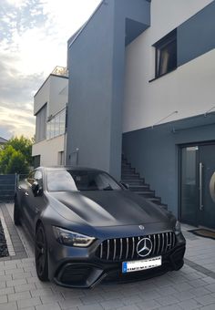 a black sports car parked in front of a building with stairs leading up to it