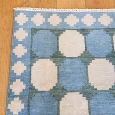 a blue and white rug with squares on the floor next to a wooden table top