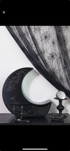 a black and white clock sitting on top of a table next to a window curtain