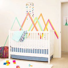 a white crib in a room with colorful wallpaper and toys on the floor