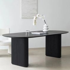 a black table with two white vases on it and a chair in the background