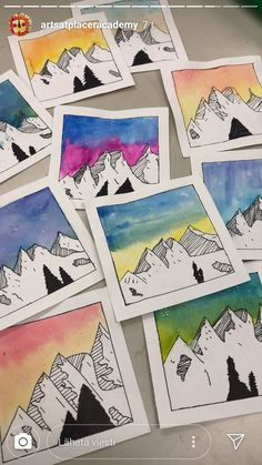 several pictures of mountains are shown on the table with watercolor paper and pencils