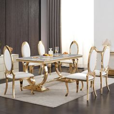 a dining table with white chairs and gold accents