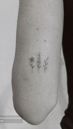 three small flowers tattoo on the left inner arm