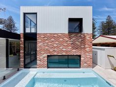 an empty swimming pool in front of a brick building with glass doors on the side