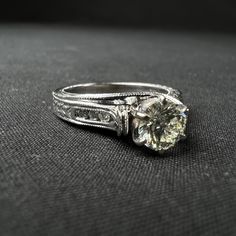 a close up of a diamond ring on a black cloth surface with the center stone visible