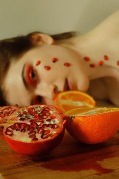 a woman laying down next to an orange cut in half on top of a table