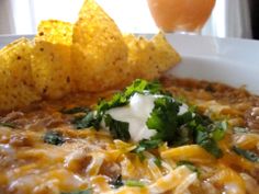 a white bowl filled with chili, cheese and tortilla chips