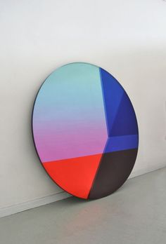 a colorful piece of art sitting on top of a white floor next to a wall