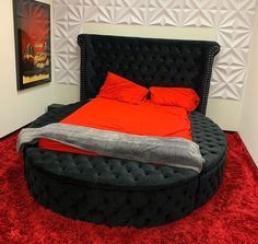 a bed that is in the middle of a red carpeted room with a black round bed