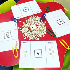 a red table topped with lots of cards and scissors next to cut outs on top of it