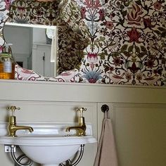 a bathroom sink sitting under a mirror next to a wall mounted faucet and towel rack