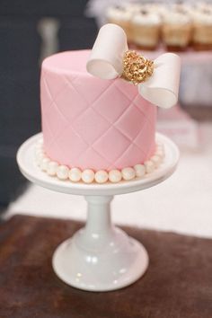 a pink and white cake sitting on top of a table