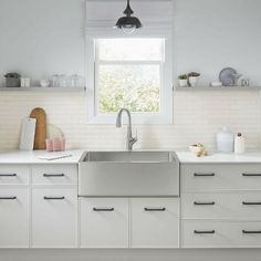 a kitchen with white cabinets and stainless steel sink under a window that looks out onto the outdoors