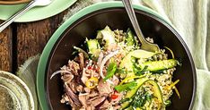 a bowl filled with meat and veggies on top of a table next to a glass of water