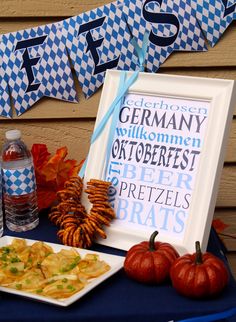 a table topped with food next to a blue and white sign that says german will come oktoberfest