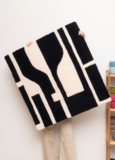 a woman holding up a black and white rug