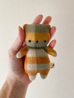 a hand holding a small stuffed animal in it's right hand