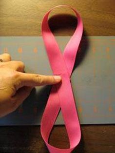 a person is pointing at a pink ribbon