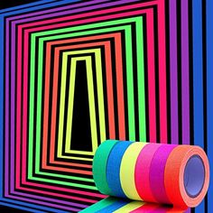 a roll of tape sitting on top of a rainbow colored wall next to a black hole