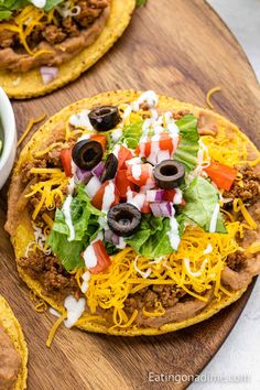 three tacos with meat, cheese and lettuce on a wooden platter