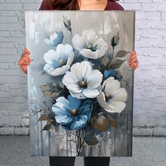 a woman holding up a large painting with flowers on it's back and sides