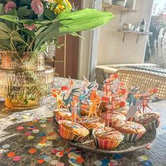 cupcakes on a table with flowers in a vase