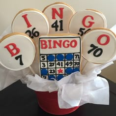 some decorated cookies in a red bucket with white and black numbers on them are sitting next to each other