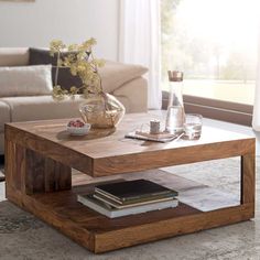 a coffee table that has some books on it and a vase with flowers in it