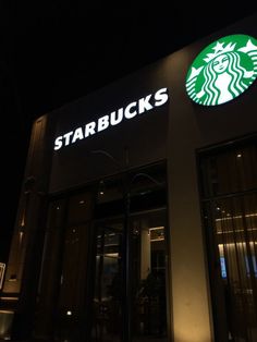 the starbucks sign is lit up at night