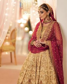 a woman in a red and gold bridal outfit standing next to a chandelier