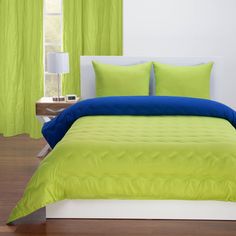 a bed with green sheets and blue pillows