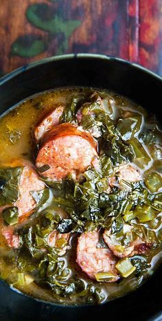 green gumbo soup with sausage and greens in a black bowl