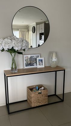 a vase with white flowers sitting on top of a wooden table next to a mirror