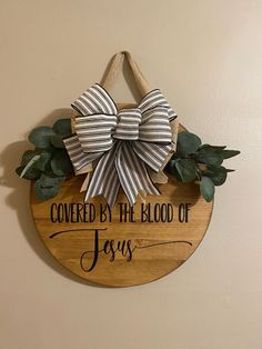 a wooden sign that says covered by the blood of jesus with a bow on it