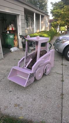 a pink snow plow sitting in front of a garage