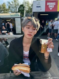 a man sitting at a table with a hot dog and drink