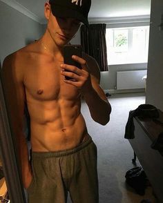 a shirtless man is looking at his cell phone in the mirror while taking a selfie